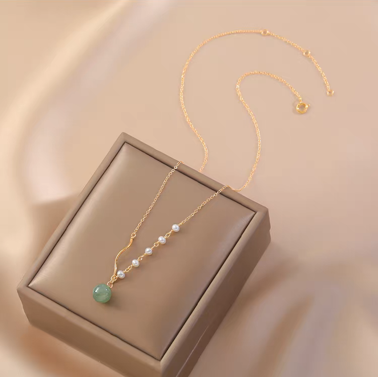 Handmade 14K gold plated Hetian jade and freshwater pearl necklace on soft fabric background
