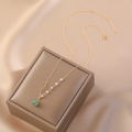Handmade 14K gold plated Hetian jade and freshwater pearl necklace on soft fabric background
