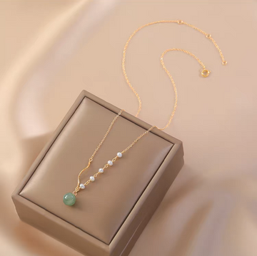 Handmade 14K gold plated Hetian jade and freshwater pearl necklace on soft fabric background
