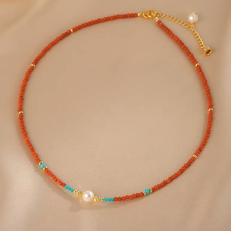 Handmade red agate and freshwater pearl beaded necklace on neutral background