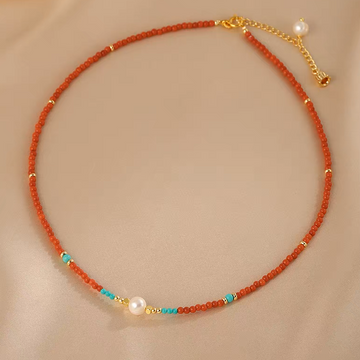 Handmade red agate and freshwater pearl beaded necklace on neutral background