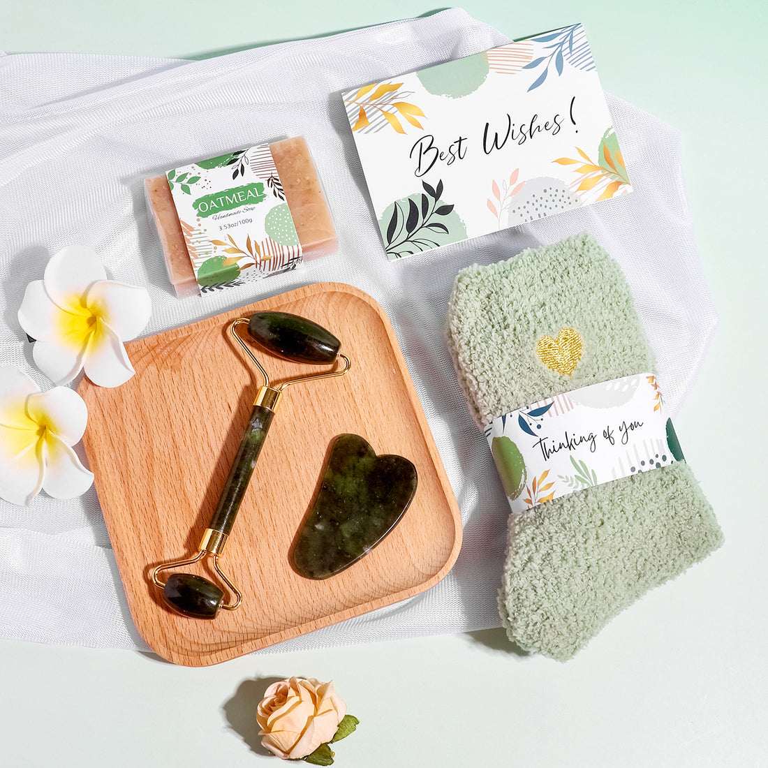 Green wellness gift box with blanket, tumbler, jade roller set, socks, candle, oatmeal soap, bath bomb and sleep mask.