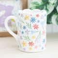 White ceramic scalloped mug with pastel floral print — perfect spring gift for Mum or floral lovers.