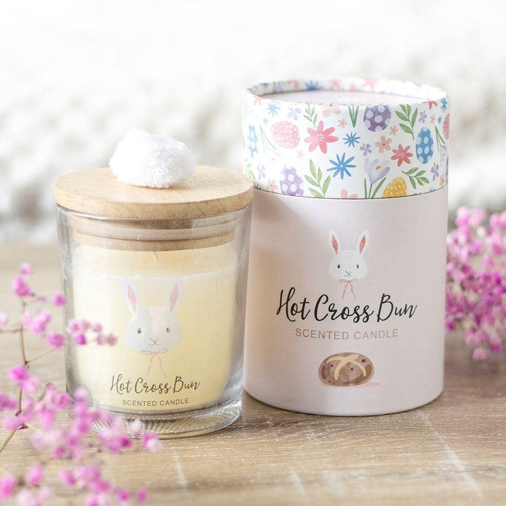 Hot Cross Bun scented candle with bunny design and pom pom lid, packaged in floral Easter gift box.