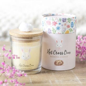 Hot Cross Bun scented candle with bunny design and pom pom lid, packaged in floral Easter gift box.