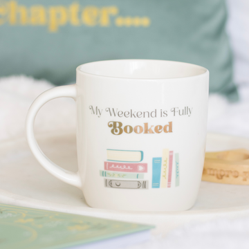 White ceramic mug with “My Weekend is Fully Booked” text and book stack design — perfect gift for book lovers.