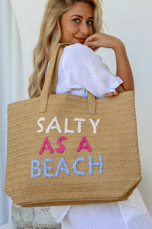 Woman holding woven straw tote bag with “Salty as a Beach” text – summer women’s beach bag and gift for her