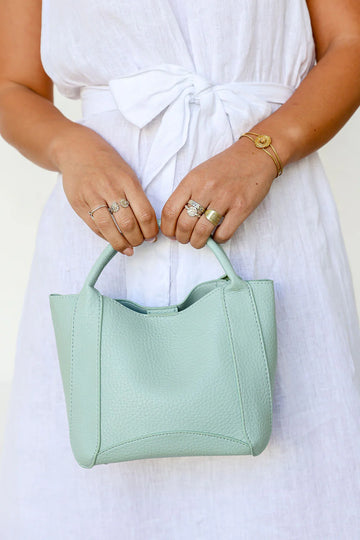 Woman holding a mint elegant handbag made from vegan leather – stylish women’s bag and perfect gift for her