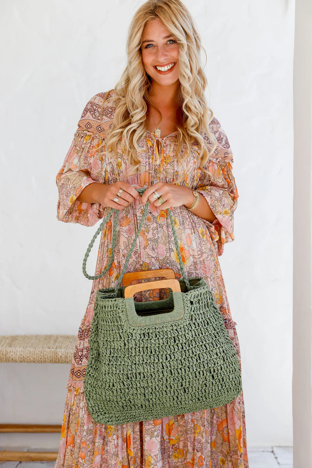 Woman holding a khaki woven tote bag with wooden handles – lightweight summer handbag and stylish gift for her