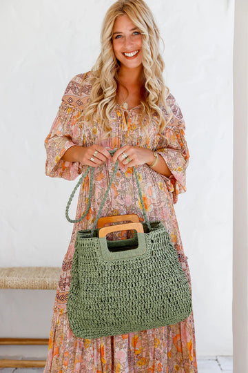 Woman holding a khaki woven tote bag with wooden handles – lightweight summer handbag and stylish gift for her