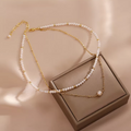 Handmade 14K gold plated freshwater pearl necklace on beige background