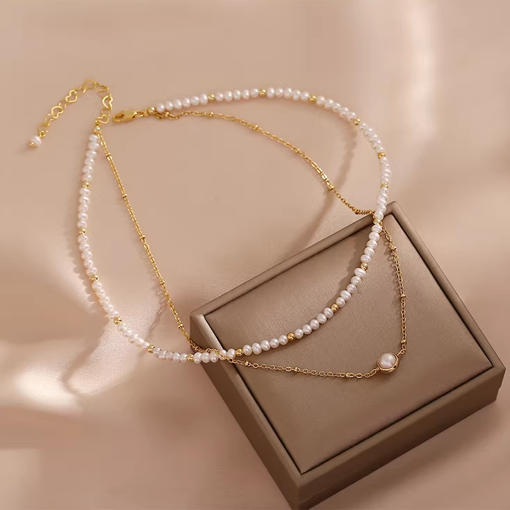 Handmade 14K gold plated freshwater pearl necklace on beige background