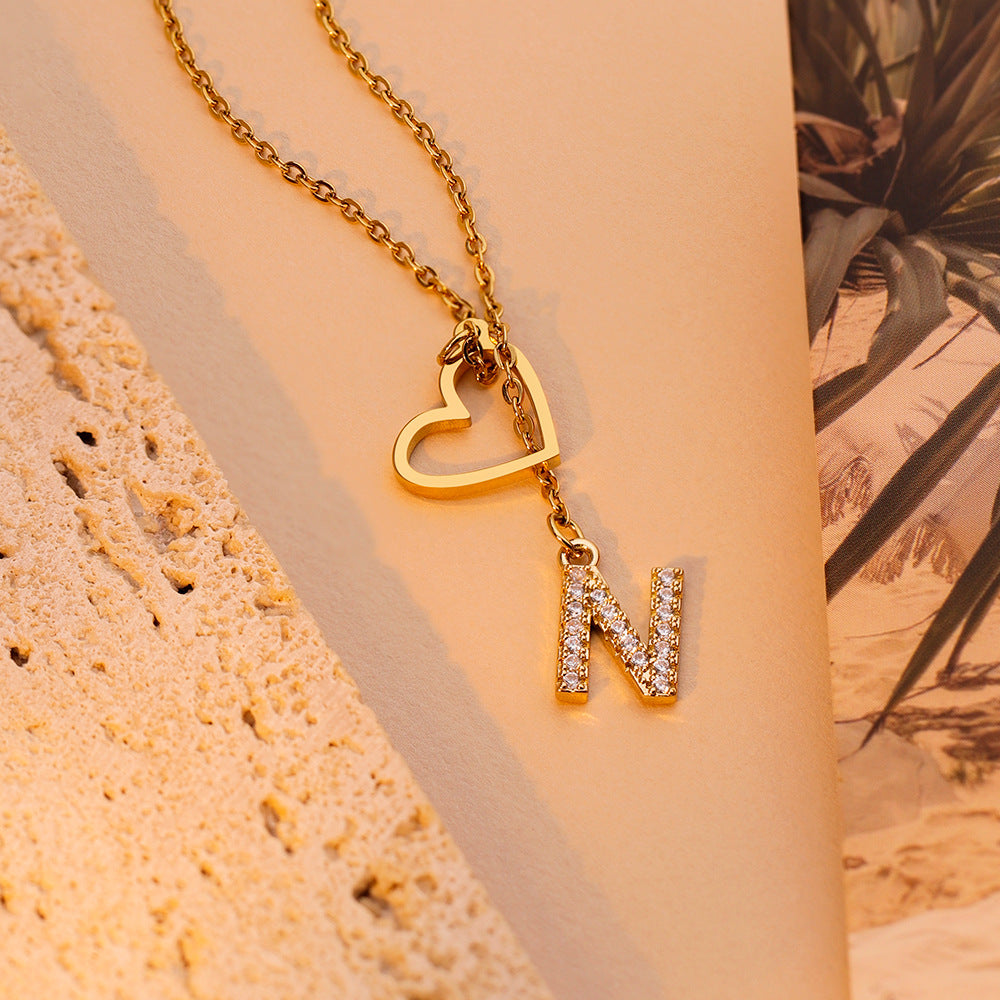 Gold heart and initial necklace worn on model with sparkling letter pendant